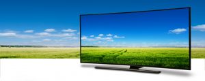 a television showing large green field beneath blue sky, with the same field behind the TV
