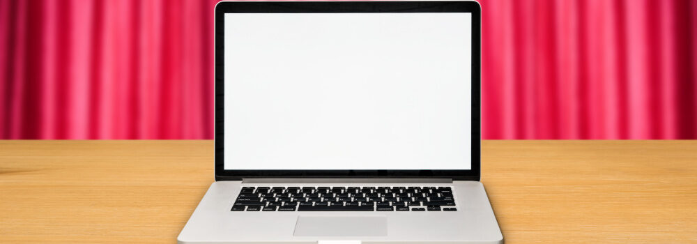 Photo of laptop with red theatre curtain in the background